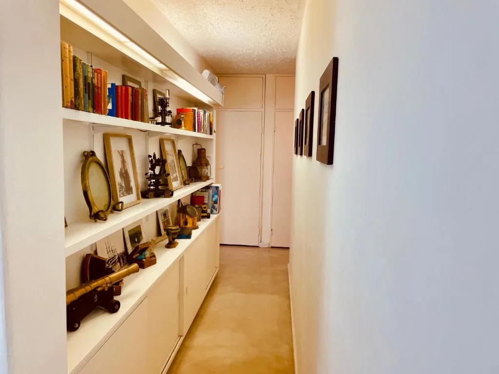 Hallway shelving displaying decorative books, artwork, and collectible items