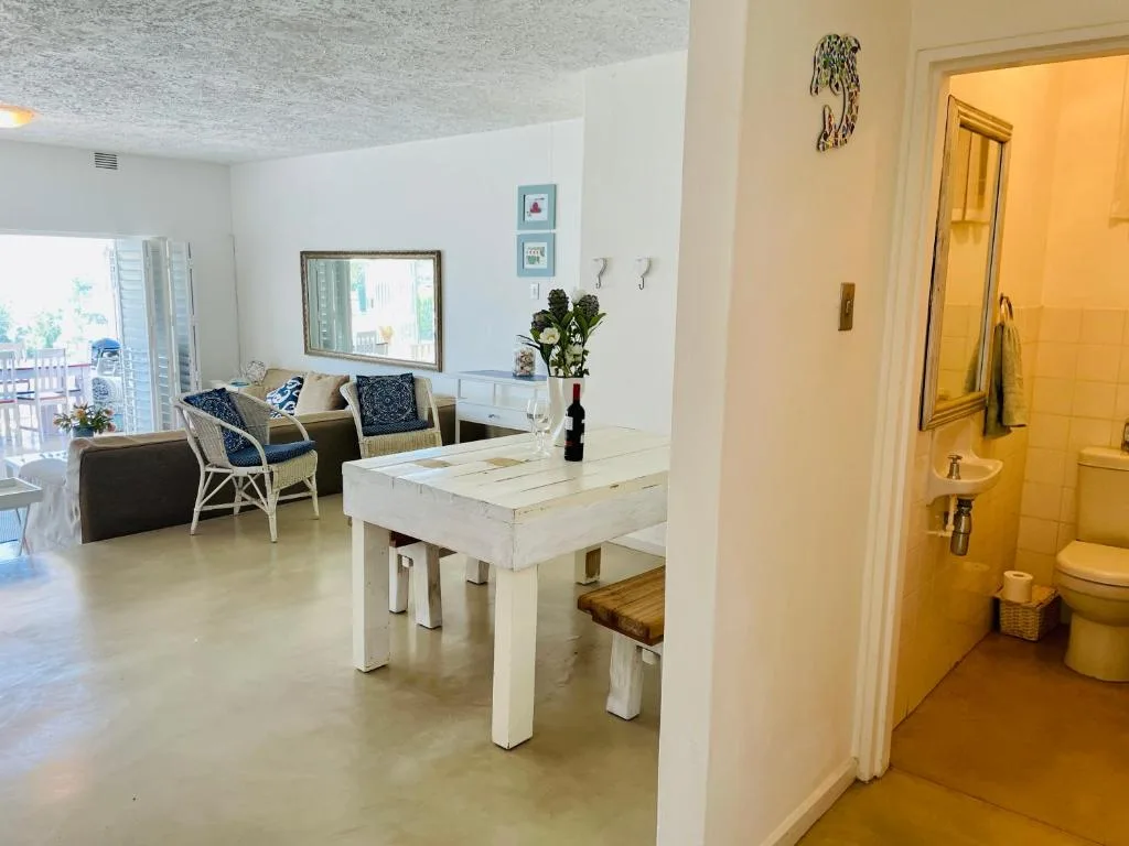 Open-plan dining area with white table and woven chairs overlooking lounge