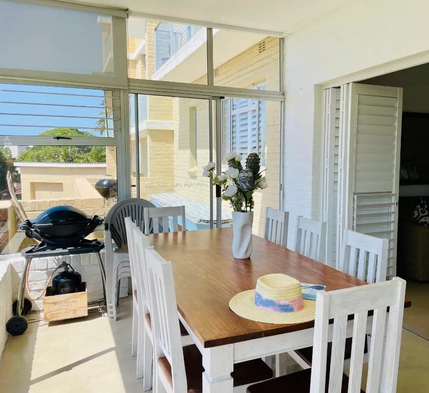 Dining table with white chairs overlooking deck and ocean view