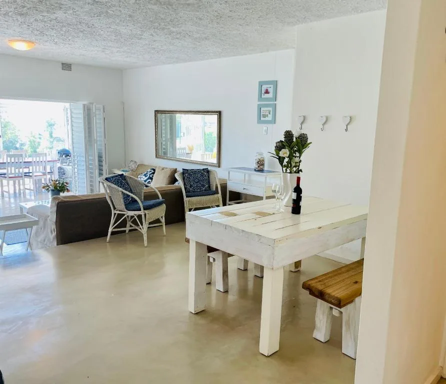 Open-plan dining and lounge area with white wooden table and natural light