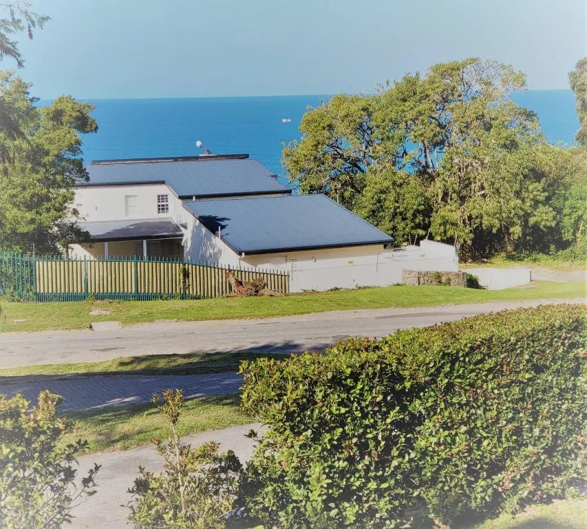 Modern white house with dark roof overlooking ocean and gardens