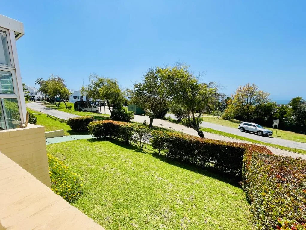 Manicured garden with lawn, hedges, and mature trees near property
