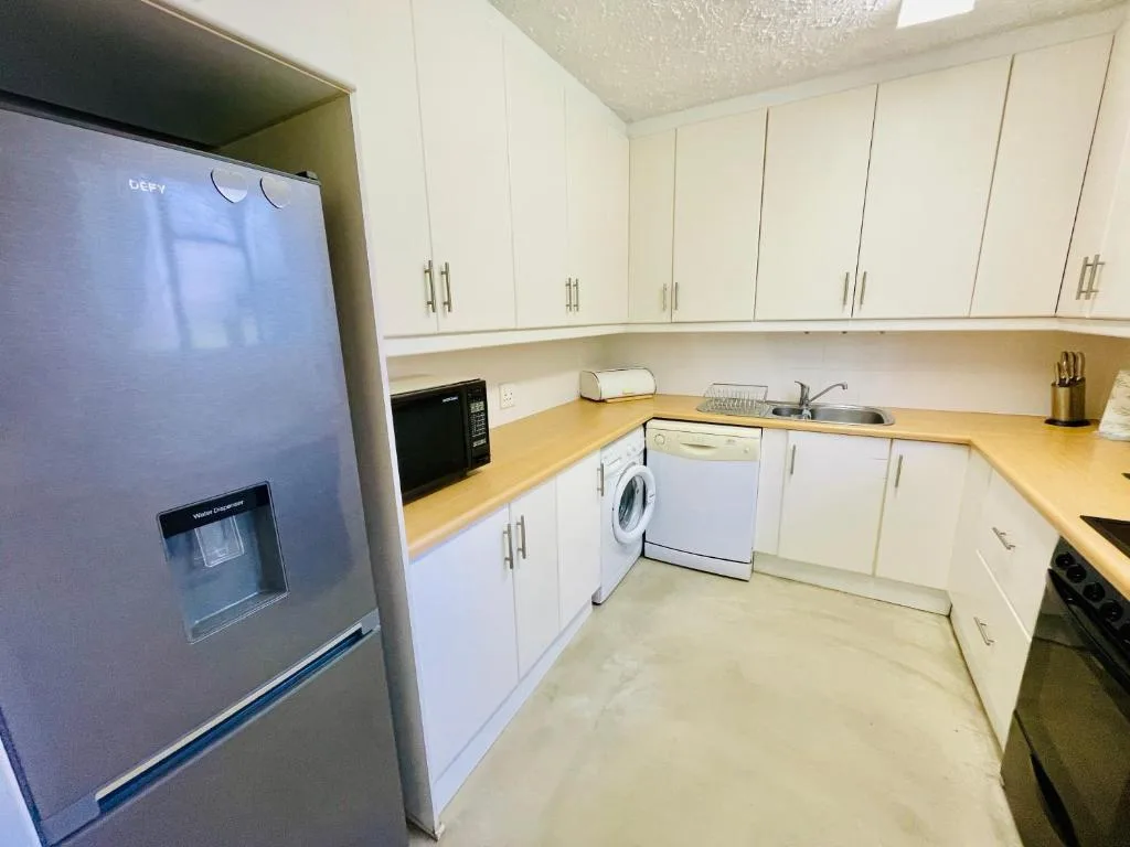 Modern kitchen with white cabinetry, stainless steel appliances, and wooden countertop