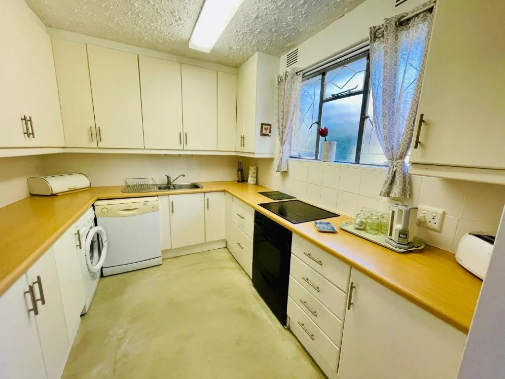 Compact kitchen with cream cabinets, yellow countertops, stove, and washing machine