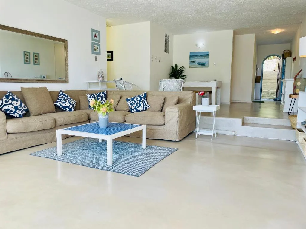 Spacious lounge with beige sectional sofa, blue and white coffee table, coastal decor.