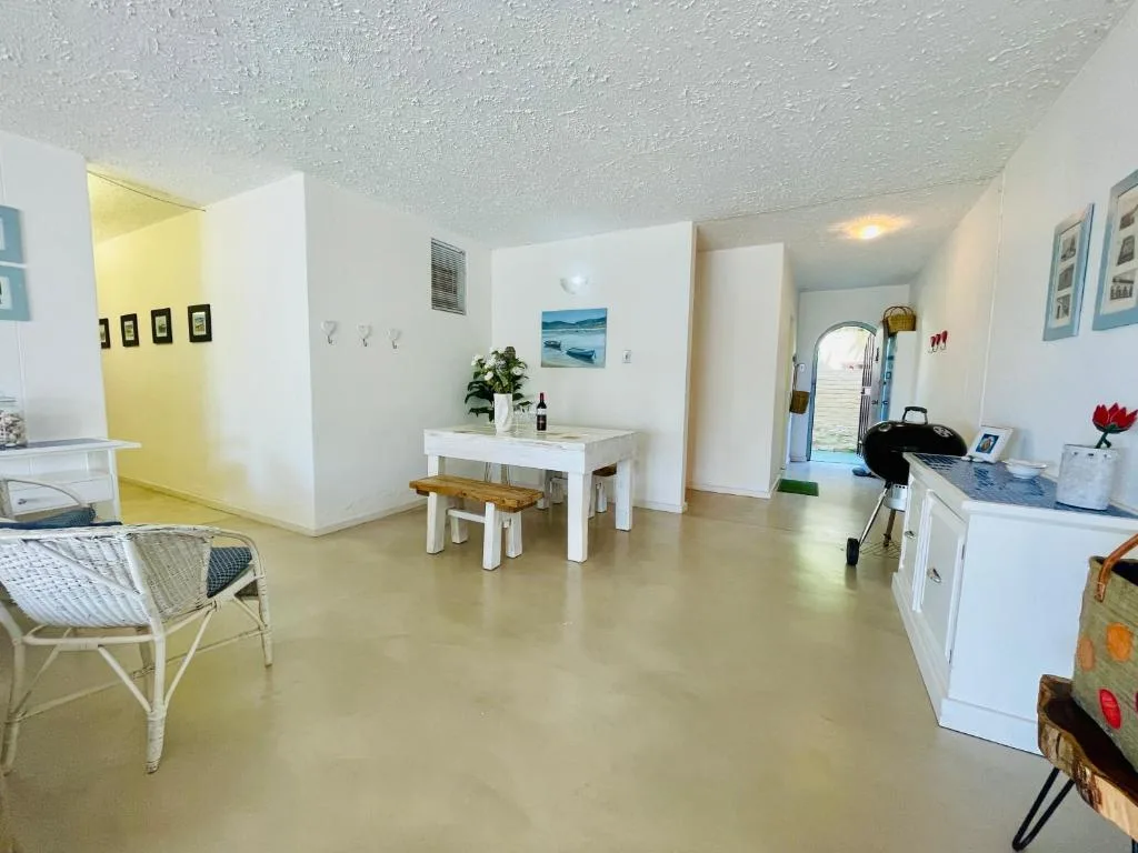 Open-plan living area with dining table, seating, and kitchen appliances visible