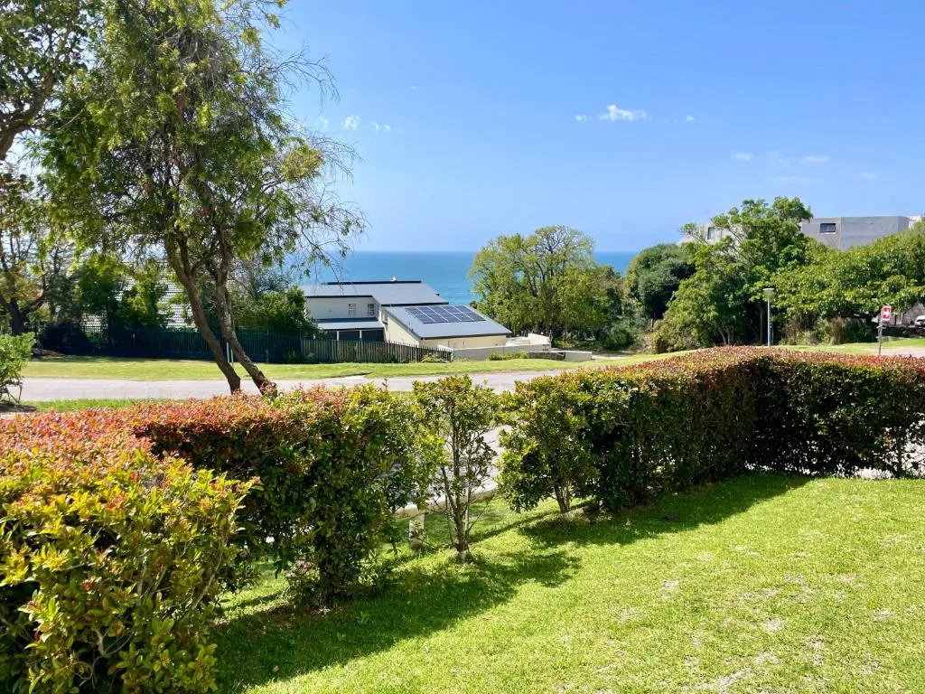 Ocean vista visible beyond manicured garden and coastal property architecture