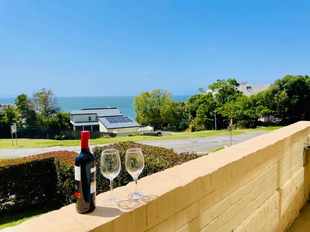 Coastal ocean view with wine glasses and bottle on deck railing