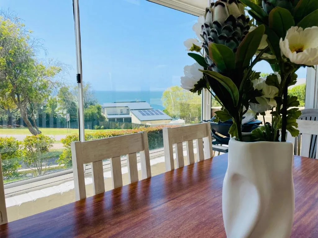 Ocean vista through dining room windows with white flowers in foreground