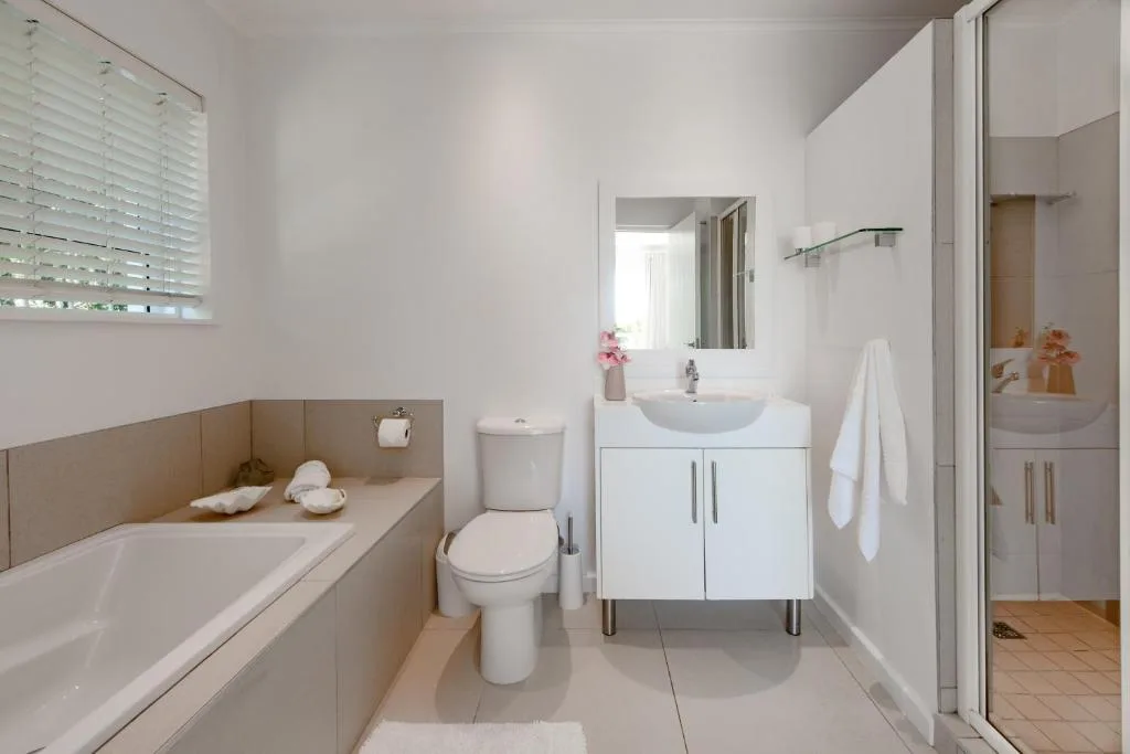 Modern bathroom with white vanity, toilet, bathtub, and shower enclosure