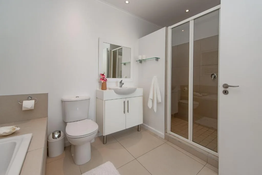 Modern bathroom with white vanity, toilet, and glass-enclosed shower cubicle