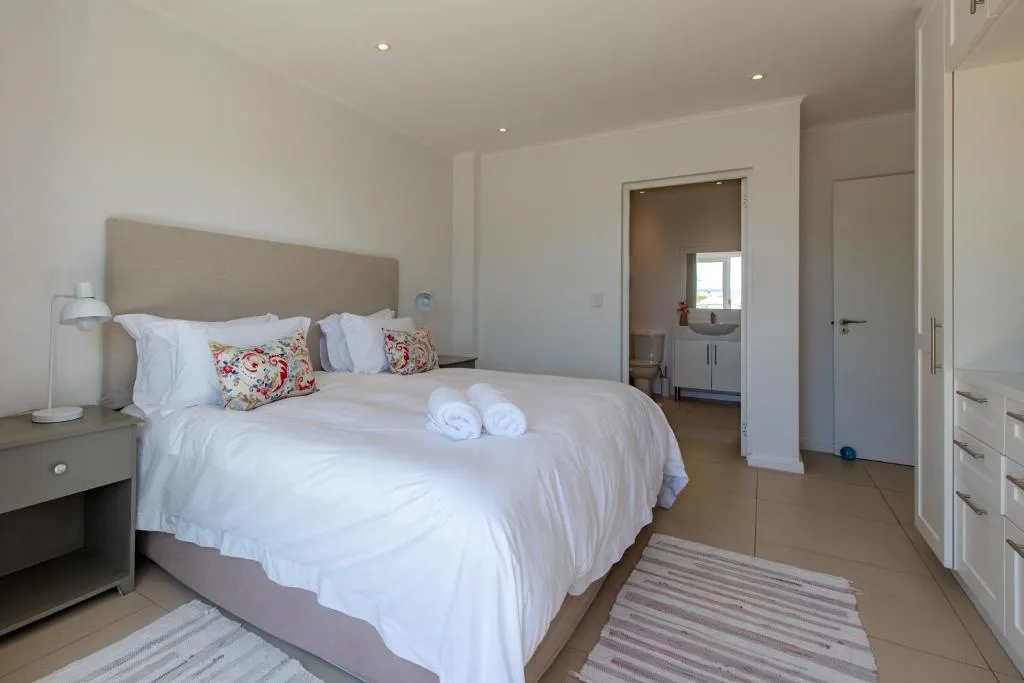 Spacious bedroom with queen bed, fresh white linens, and ensuite bathroom access