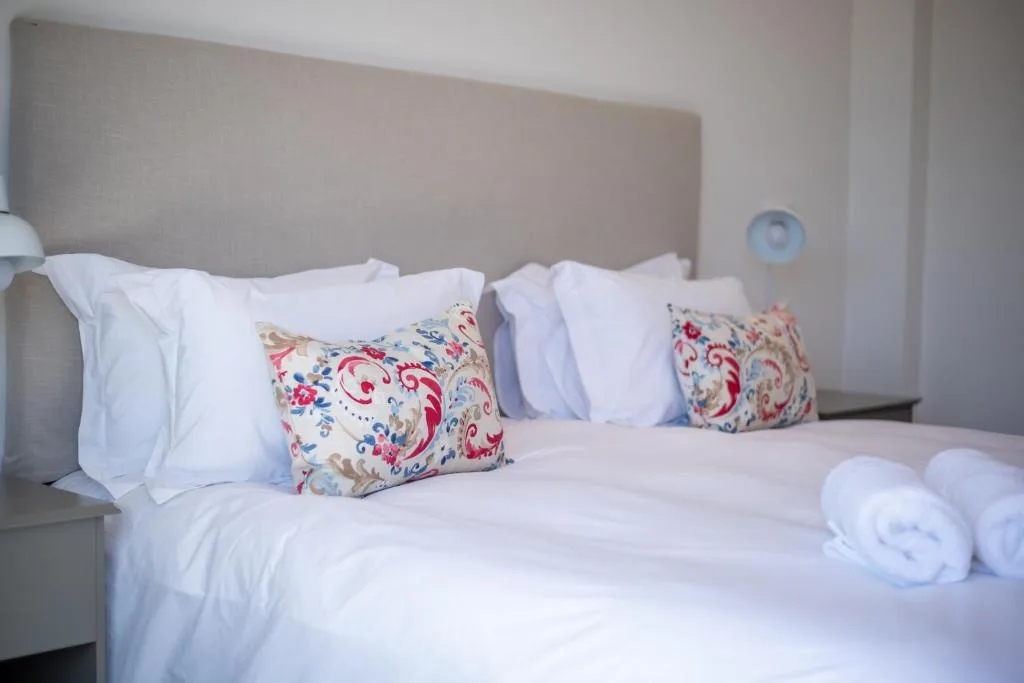 Neatly made bed with white linens and decorative floral pillows