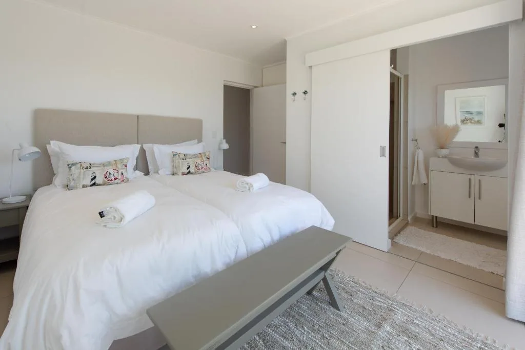 Spacious bedroom with twin beds, neutral headboard, and ensuite bathroom visible