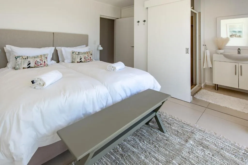 Spacious bedroom with twin beds, neutral decor, and ensuite bathroom visible