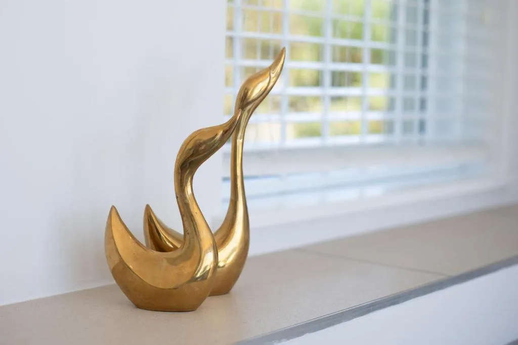 Gold sculptural ornament on windowsill with garden views beyond