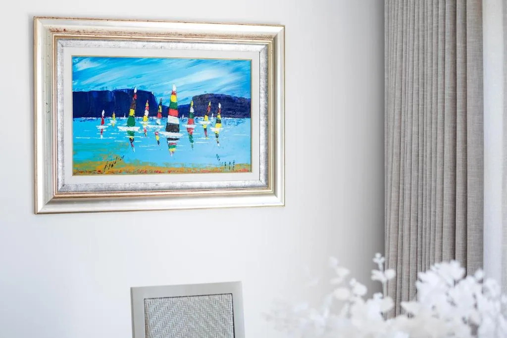 Framed colorful sailing boat artwork hanging on interior wall