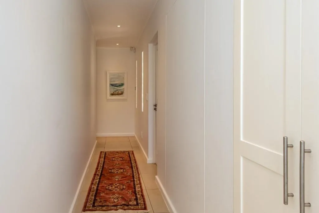 Bright hallway with red runner rug and framed coastal artwork