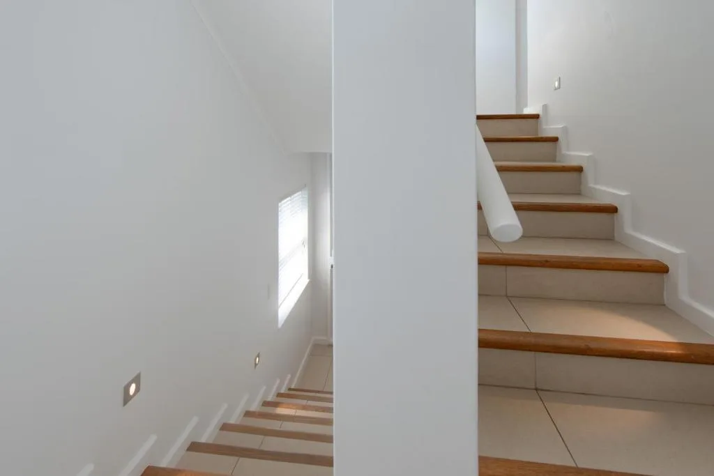 Clean modern staircase with wooden steps and white walls, interior detail