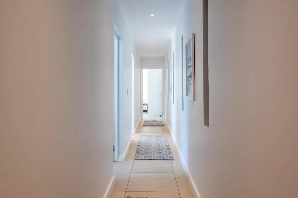 Bright modern hallway with white walls, tiled flooring, and artwork