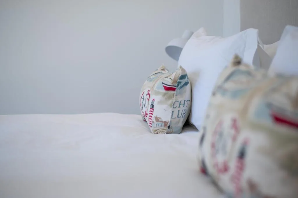 Decorative seaside pillows with lighthouse and nautical patterns on bed