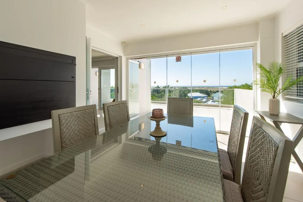 Modern dining table with chairs overlooking scenic landscape views through large windows