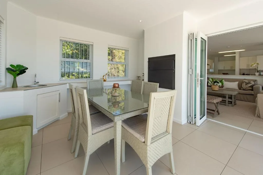 Modern dining area with glass table and upholstered chairs, garden views