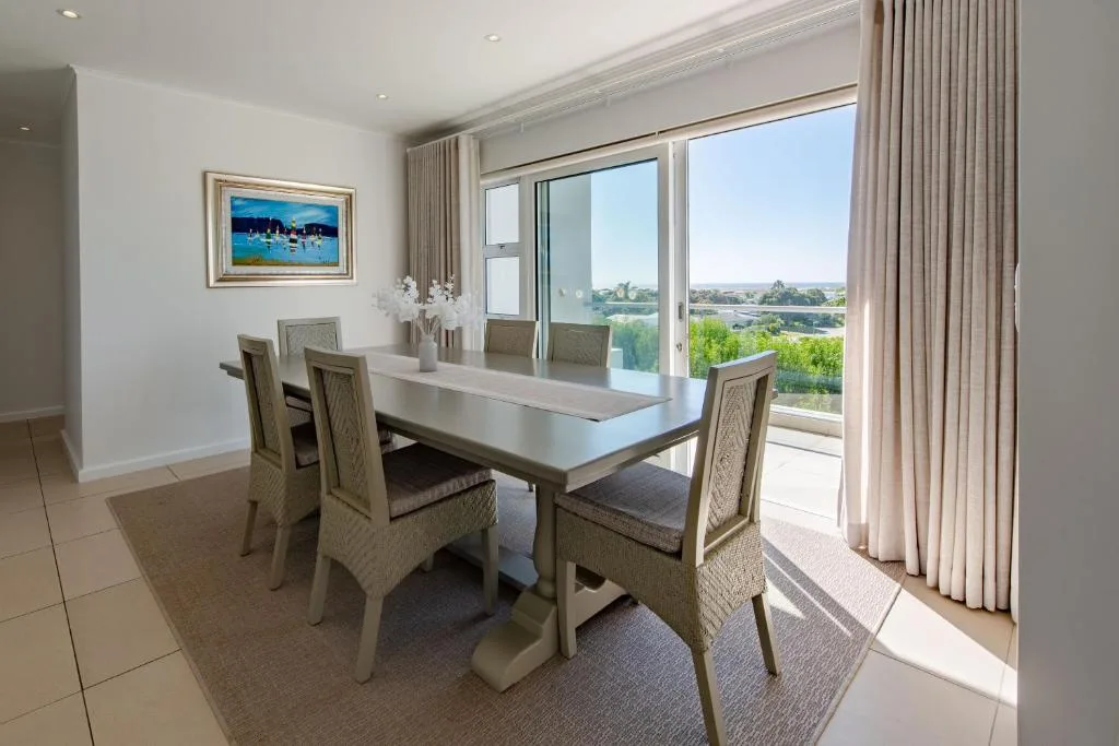 Modern dining room with white table, upholstered chairs, scenic lagoon views