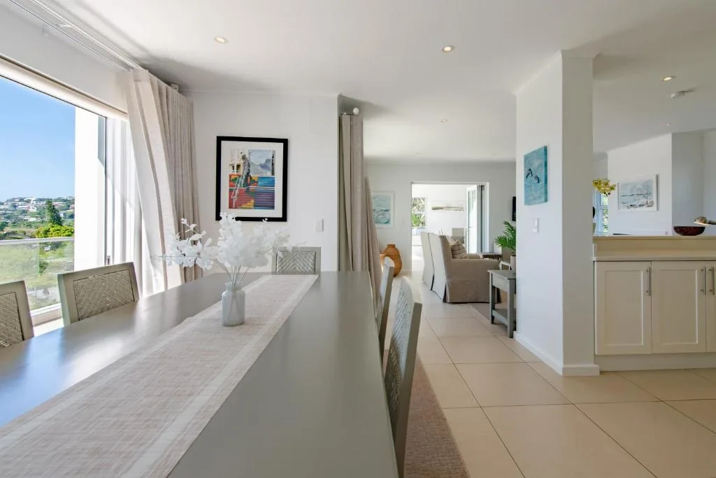 Modern dining table with ocean view through large windows and countryside beyond