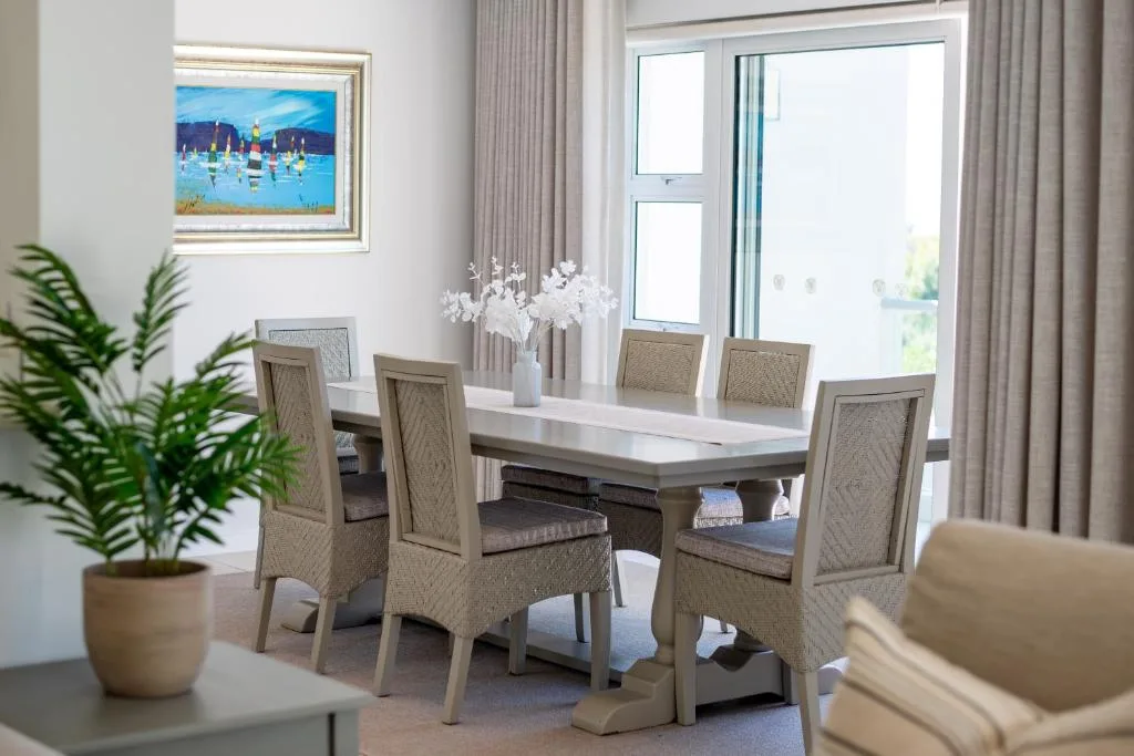 Modern dining table with upholstered chairs and white floral centerpiece