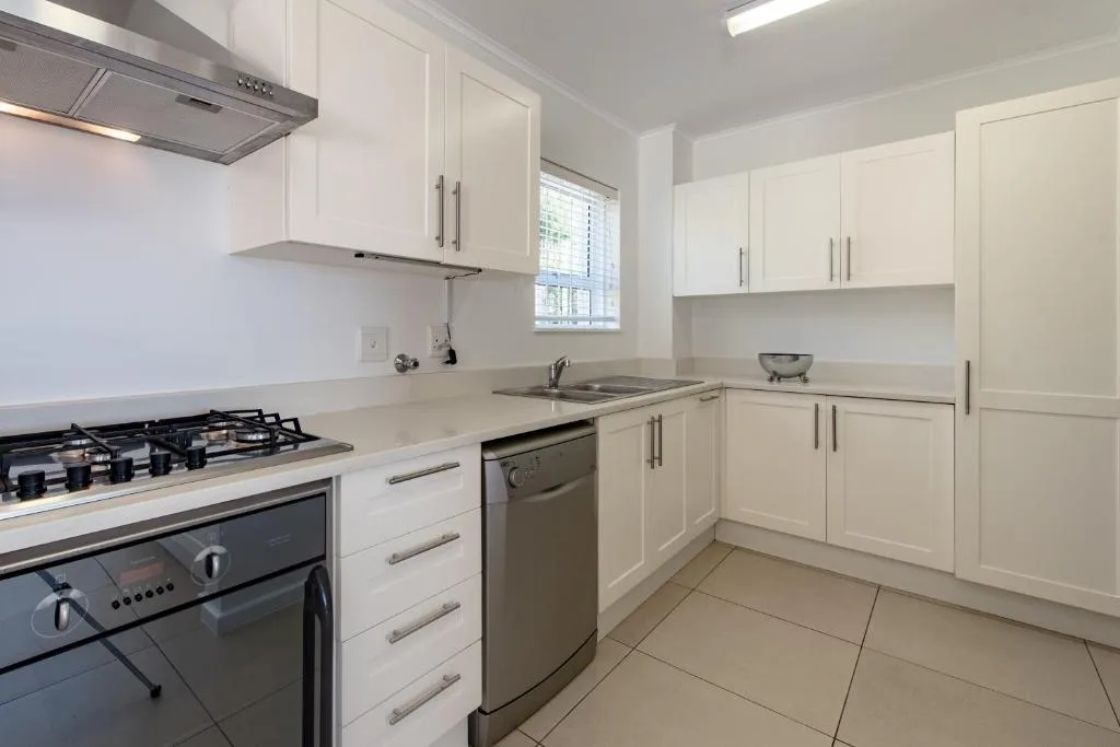 Modern white kitchen with gas stove, stainless steel appliances, and tile flooring