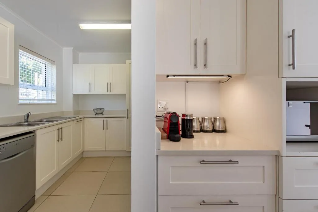 Modern white kitchen with cabinetry, stove, and coffee maker appliances