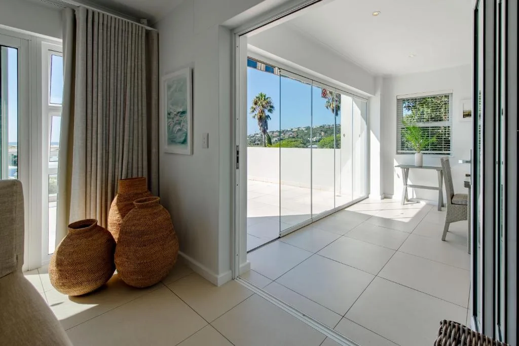 Bright modern lounge with sliding glass doors overlooking coastal deck and gardens