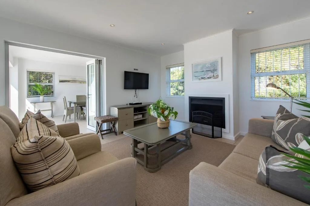 Bright modern lounge with neutral furnishings, fireplace, and wall-mounted television