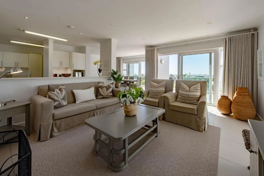 Spacious open-plan lounge with sofa, armchairs, and panoramic views