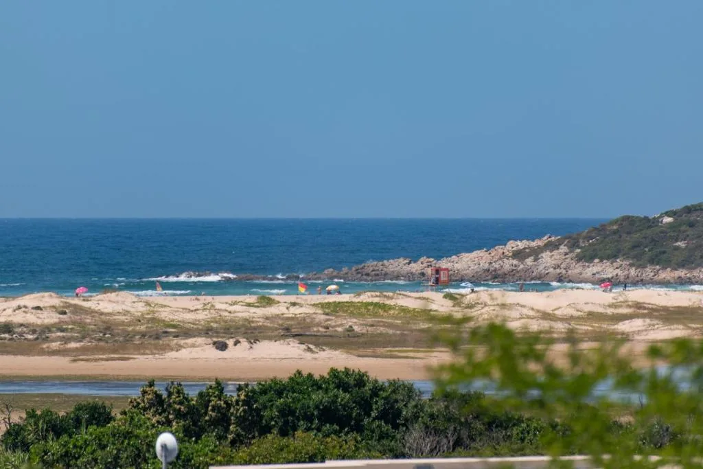 Panoramic coastal view with sandy beach, rocky outcrops, and turquoise ocean waters
