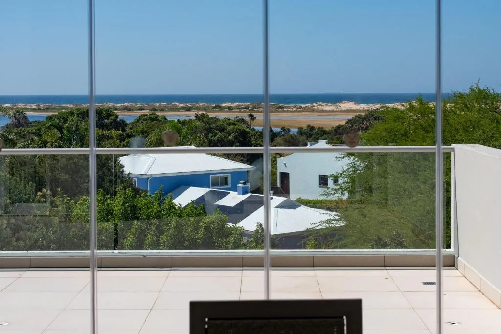 Coastal lagoon and ocean vista framed through large windows from interior