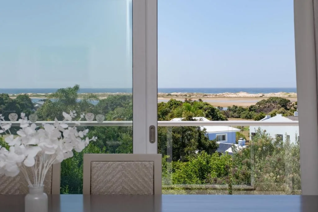 Scenic lagoon and coastline vista through large windows with white flowers