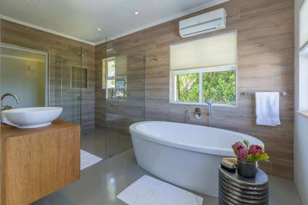 Modern bathroom with freestanding tub, walk-in shower, dual vanities, and garden views