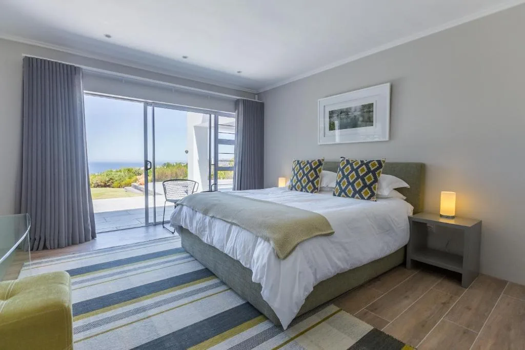 Bright modern bedroom with ocean view through glass doors and patio access