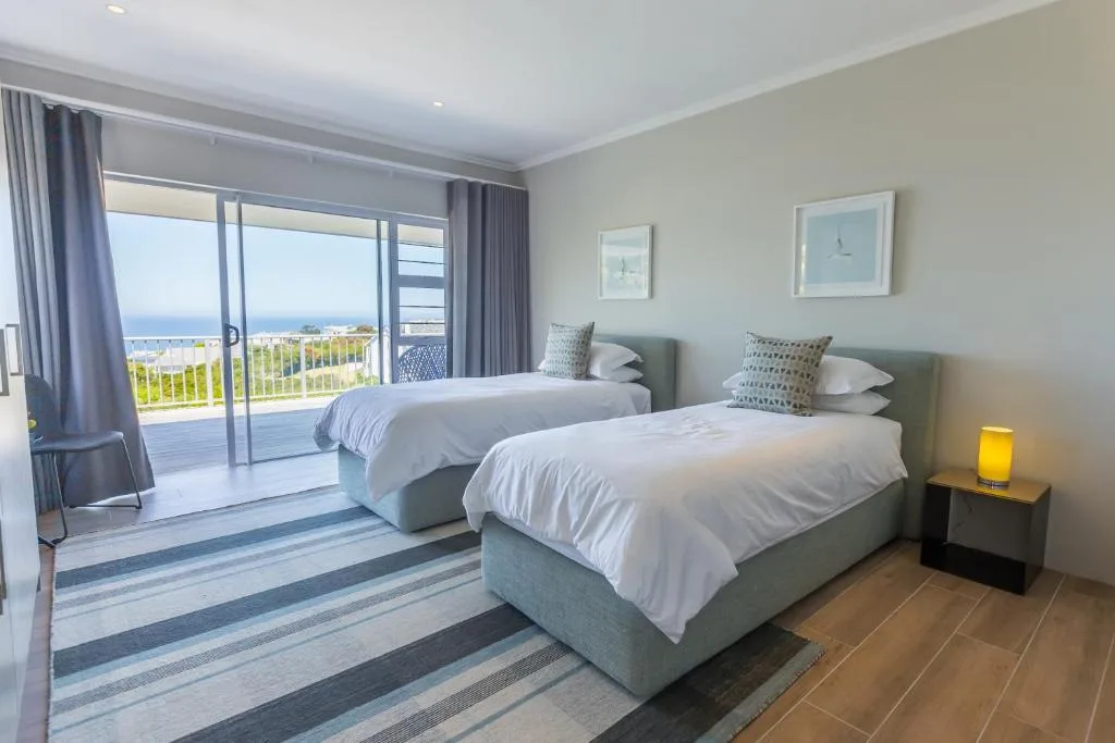Bright twin bedroom with ocean views through sliding glass doors and deck access