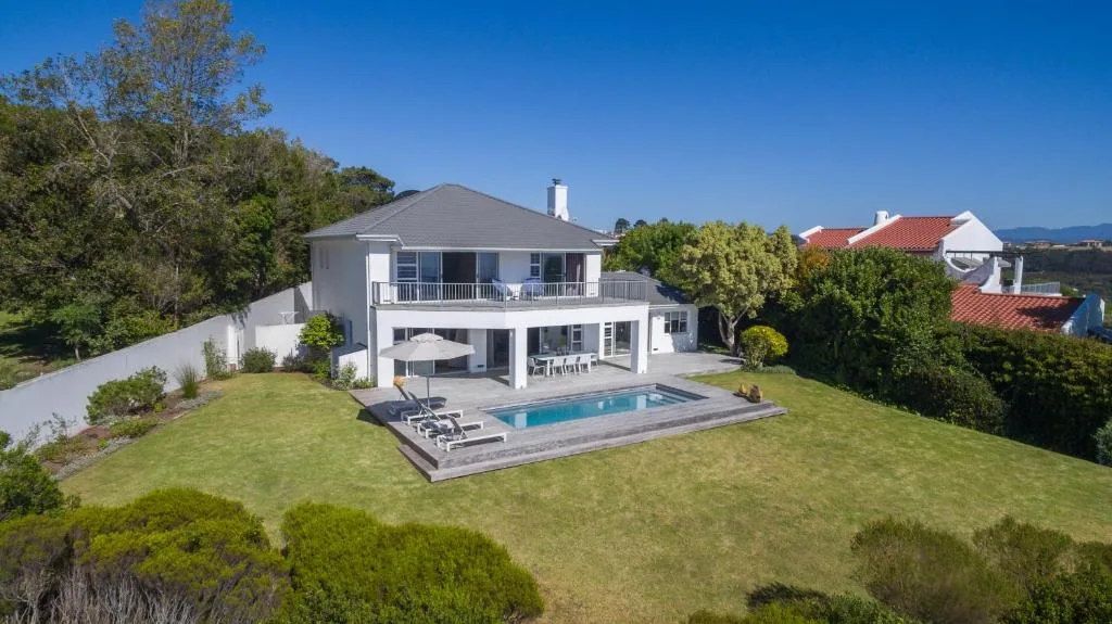 Modern white villa with pool and manicured gardens overlooking landscape