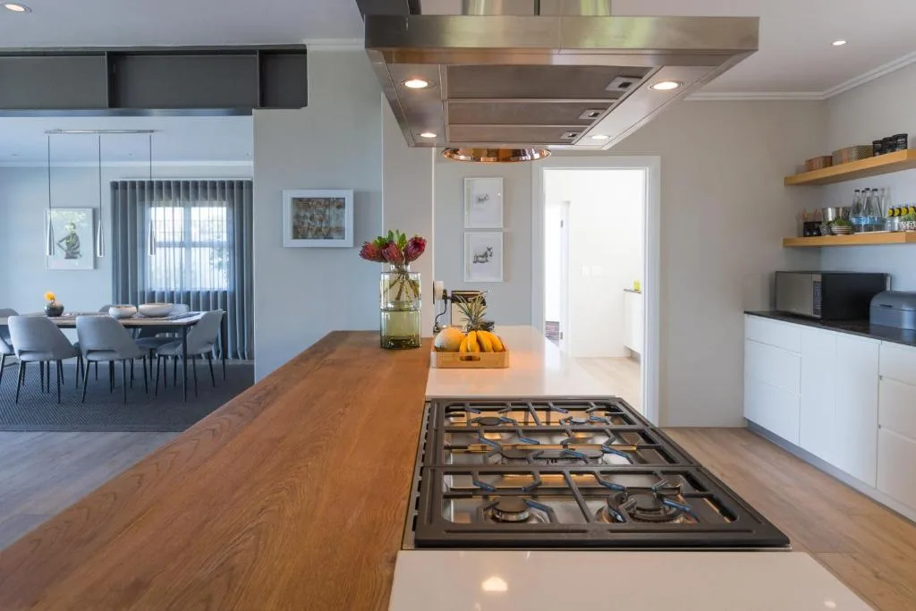 Modern kitchen with gas cooktop, wooden counters, and stainless steel hood