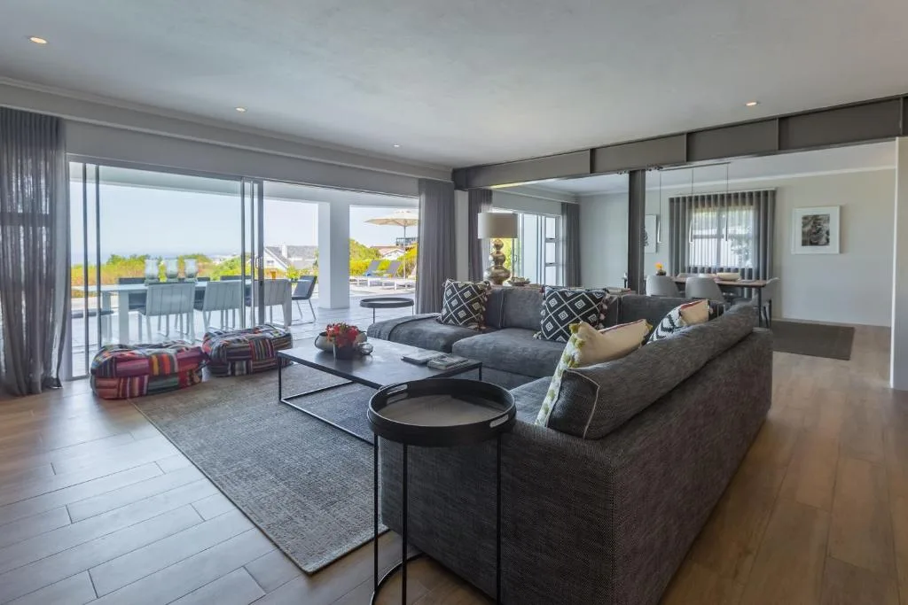 Modern lounge with gray sectional sofa, floor-to-ceiling windows overlooking deck and ocean