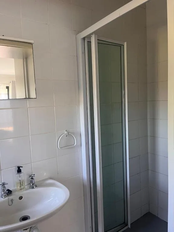 Modern bathroom with white tiles, round sink, and shower enclosure