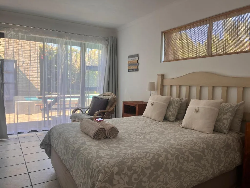Spacious bedroom with queen bed, patio doors opening to pool view