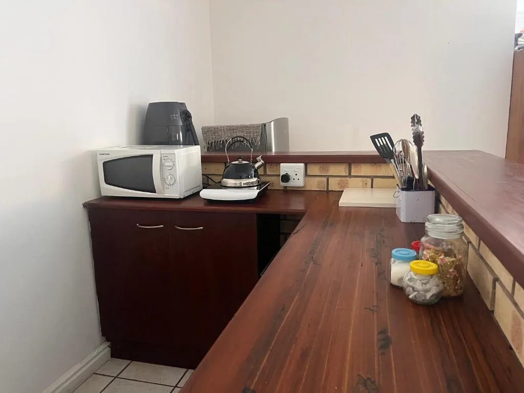 Kitchen counter with microwave, kettle, utensils and storage containers