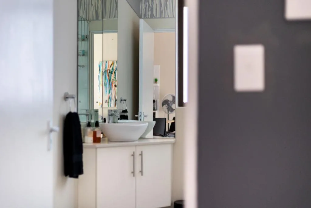 Modern bathroom with white vanity, round sink, and large mirror