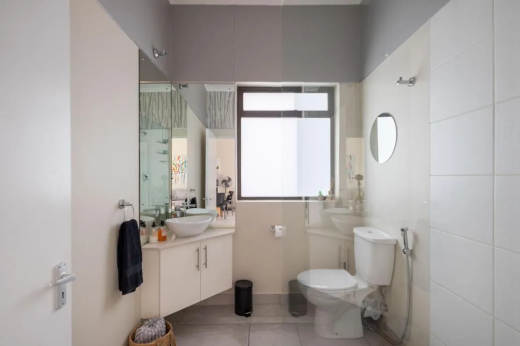 Modern bathroom with vanity, toilet, and large mirror window