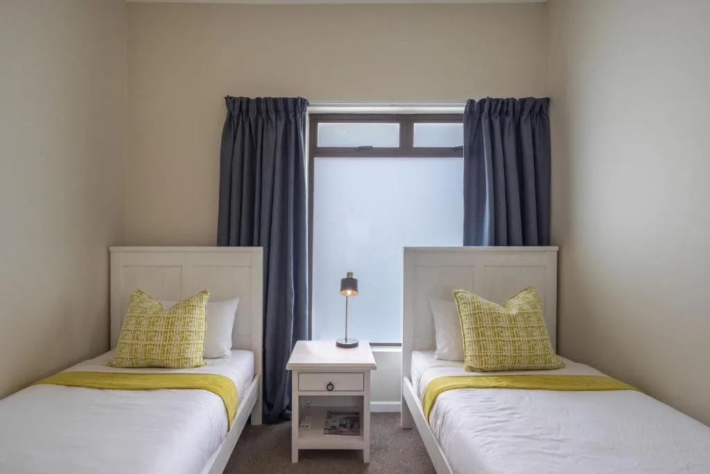 Twin bedroom with yellow accents and large windows overlooking the town